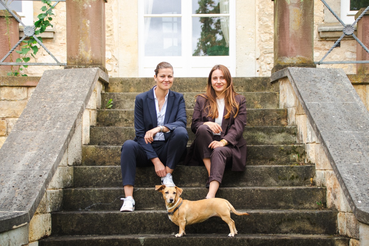 Charleen Kaub und Nina Weigelt mit Hund auf einer Treppe
