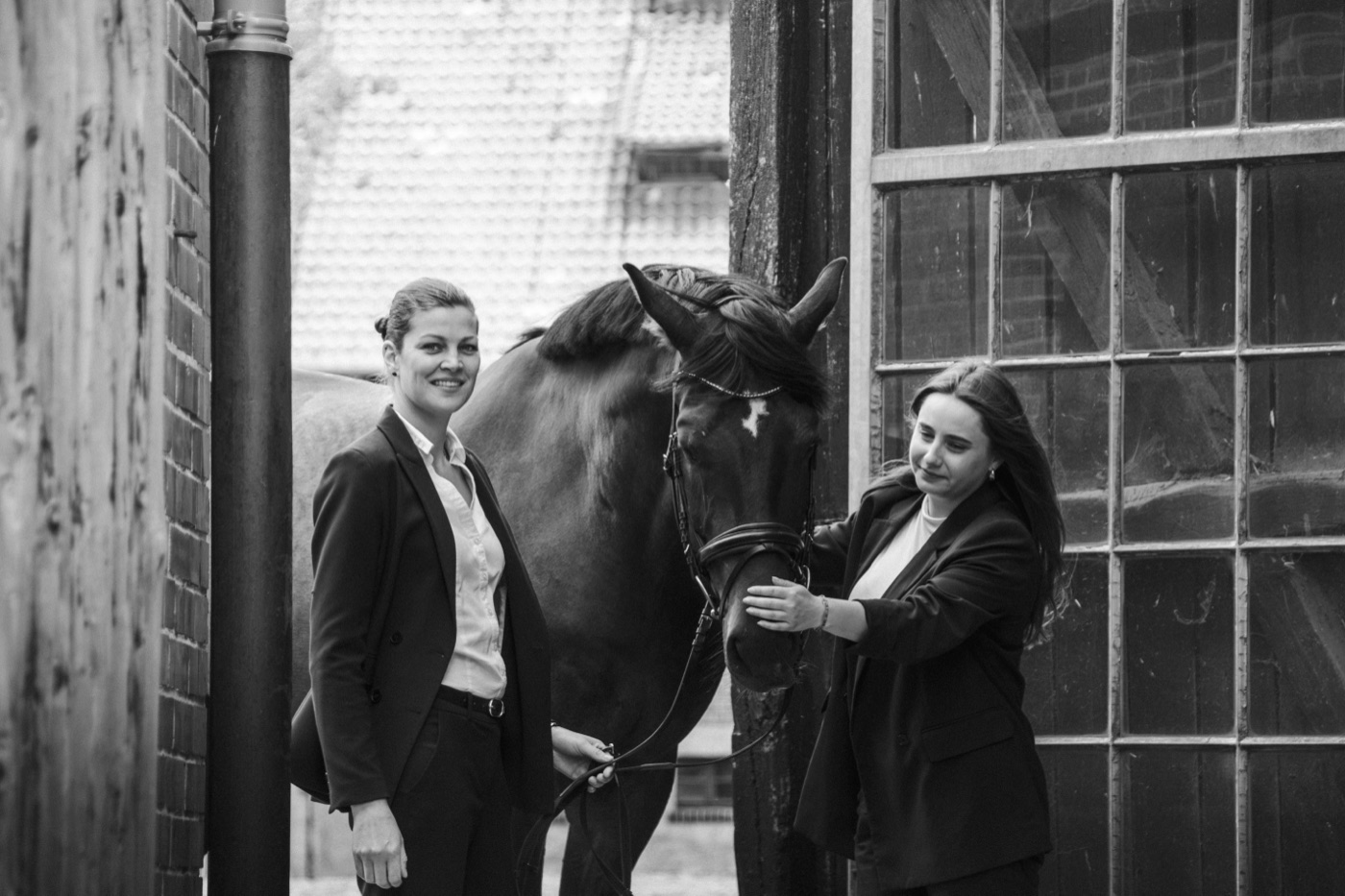 Nina Weigelt und Charleen Kaub mit einem Pferd vor einer Reithalle
